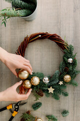 top view of florist hands making Christmas wreath on wooden tabletop. Cozy style and new year mood