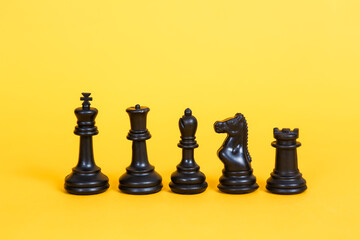 Black chessboard pieces on yellow background