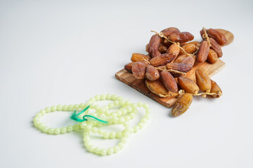 close up of dates and prayer beads with white background