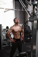 Fototapeta na wymiar Vertical shot of a shirtless sportsman with ripped body standing in the gym