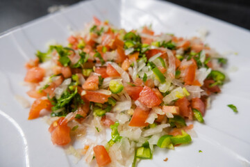 Chopped tomato, onion, and chili pepper on white plate