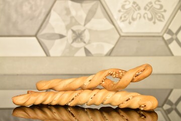 Three breadsticks grissini, close-up, on a background of tiles.