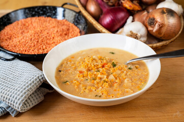 Soup from orange lentil,dried lentil, onion and garlic on table.