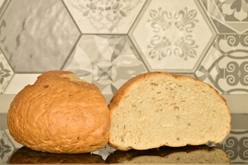 Two halves of fragrant white bread, close-up, on the background of tiles.