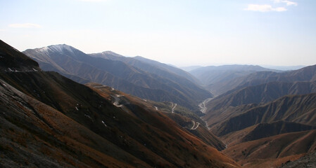 Mountain landscape on a sunny. Snowy peaks, a mountain gorge with green grass and trees....