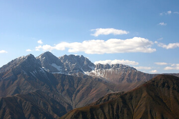 Mountain landscape on a sunny. Snowy peaks, a mountain gorge with green grass and trees....