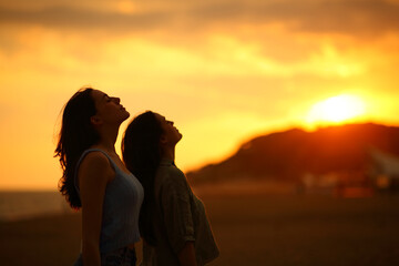 Two women silhouette breathing fresh air at sunset