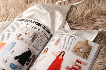 Naklejka premium Open magazine and night dress on beige fur