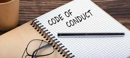 Code of Conduct words written in an office notebook. Concept in business.