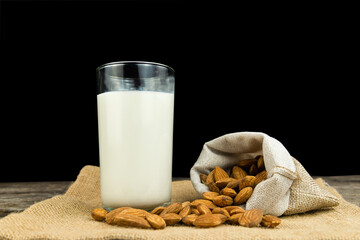Milk with almond or roasted almond on sack with a wooden table on dark background. Healthy food. Snack. Food and drink concept.