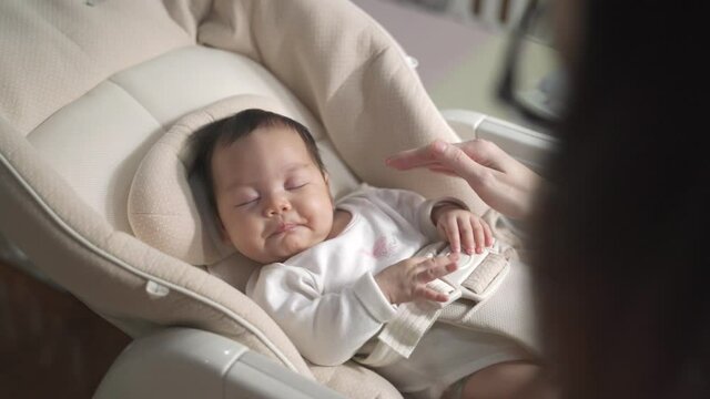 asian woman mother gently touching baby infant head with care lull to sleep on baby buggy at home. baby sleeping on baby stroller. natural authentic.