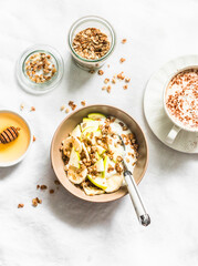 Greek yogurt with granola, banana, apple, honey on a light background, top view. Delicious breakfast