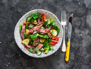 Potato, beef steak, romano and vegetable salad on a dark background, top view. Balanced diets healthy food