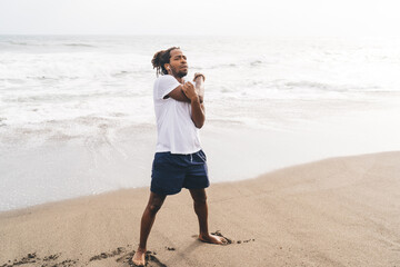 Black man stretching arms on beach