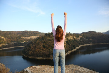 Woman raising arms celebrating vacation in a river