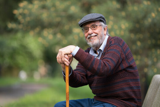 Old man with happy and serene expression sitting outdoors on a park bench