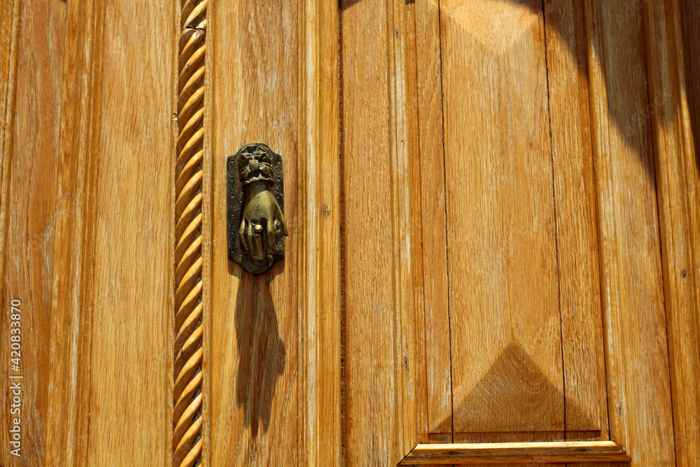 Sticker Closeup of a wooden door with a metal hand as the door handle