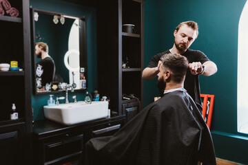 Professional hairdresser serves male client in barbershop