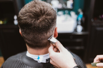 Male haircut process, back view of client's head while the hairdresser cuts hair