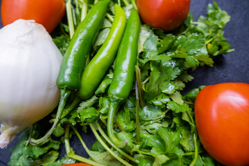Chili peppers, onion, and a tomato above coriander