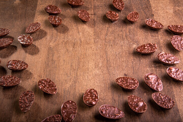Lots of mini crunchy stuffed chocolate easter eggs on a wooden table with free space in the middle.