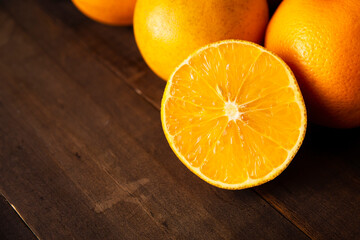 close up of a ripe orange cut in half on brown rustic wooden table