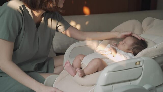 asian woman mother gently touching baby infant head with care lull to sleep on baby buggy at home. baby sleeping on baby stroller. natural authentic.