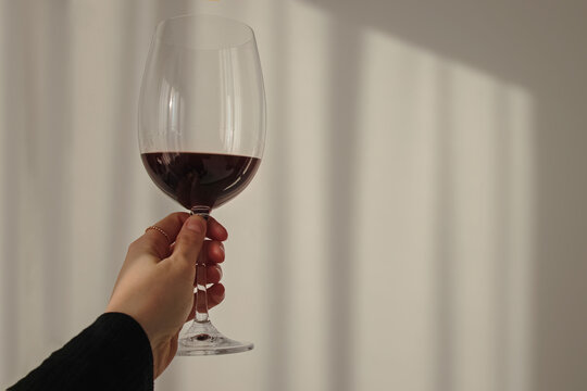Woman's hand holding glass with red wine
