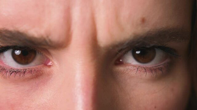 Face of angry and frowning young caucasian woman looking doubtful at camera. Dramatic close-up portrait of unfriendly girl with an unhappy face and dark brown eyes