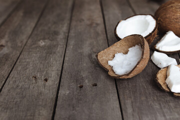 Broken coconuts on gray wooden background. White coconut pulp