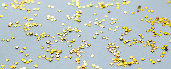Golden shiny stars glitter or confetti on gray background