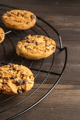 Top view of chocolate cookies on wire rack, selective focus, on wooden table, vertical, with copy space