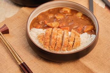 Top view Japanese curry rice topping with fried pork and vegetables in white and black plate with chopsticks. Curry rice Japanese food.