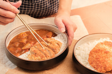 Japanese curry rice topping with fried pork and vegetables in white and black plate with chopsticks. Curry rice Japanese food.