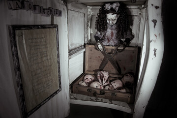 Scary doll with scissors in a small box. Severed heads of dolls. Scary face.