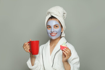 Happy woman in cosmetic face mask eating breakfast and drinking coffee. Female day routine