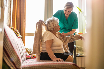 Female nurse taking care of a senior woman at home
 - obrazy, fototapety, plakaty