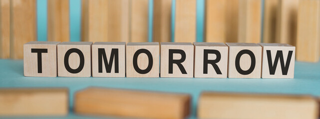 Word TOMORROW made from wooden cubes on a light background.