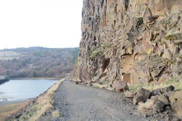 Dirt road along a rock face on a nice day.