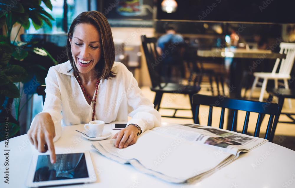 Poster cheerful female customer touching screen of gadget checking received email message and laughing, joy