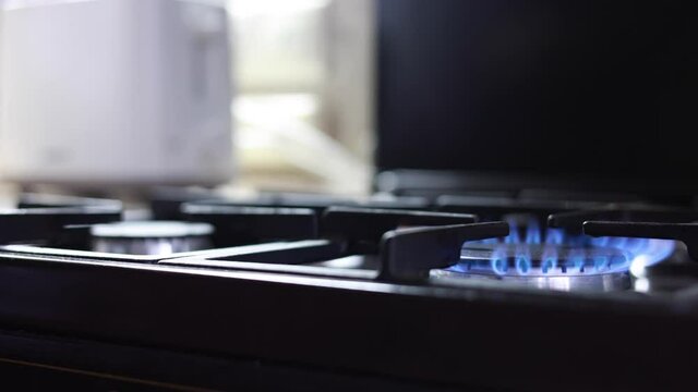 Male Hand Lighting The Fire At The Gas Stove And Putting A Frying Pan On The Blue Flame. Panning Dolly Slider Shot.