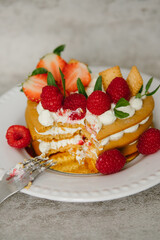 Cake with cream and strawberries in the shape of a heart on the background. Cooking.