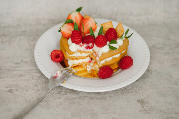 Cake with cream and strawberries in the shape of a heart on the background. Cooking.