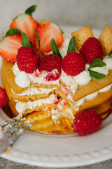 Cake with cream and strawberries in the shape of a heart on the background. Cooking.
