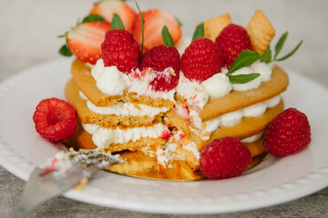 Cake with cream and strawberries in the shape of a heart on the background. Cooking.