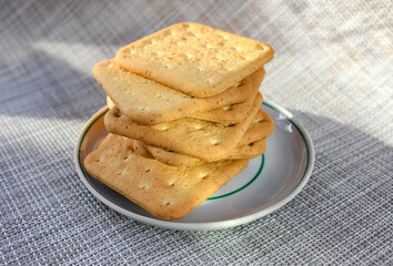 A few crackers in a saucer on the table. Natural light.