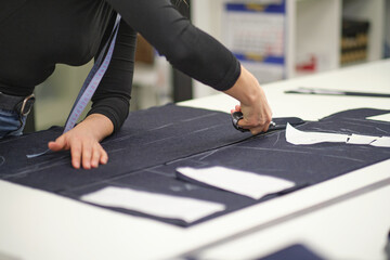 Dressmaker cutting dress fabric on sketch line. Fashion designer tailor or sewer in workshop studio designing new collection clothes. Business owner shop and entrepreneur concept