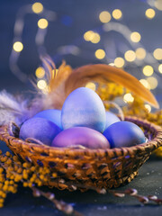 Fototapeta na wymiar Wicker basket Easter painted bed eggs, close-up on bokeh garland