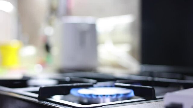 Male Hand Lighting The Fire At The Gas Stove And Putting A Frying Pan On The Blue Flame.