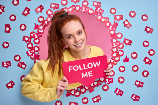 Beautiful redhead female holding FOLLOW ME sign, ask to be more active in Internet, send likes and messages